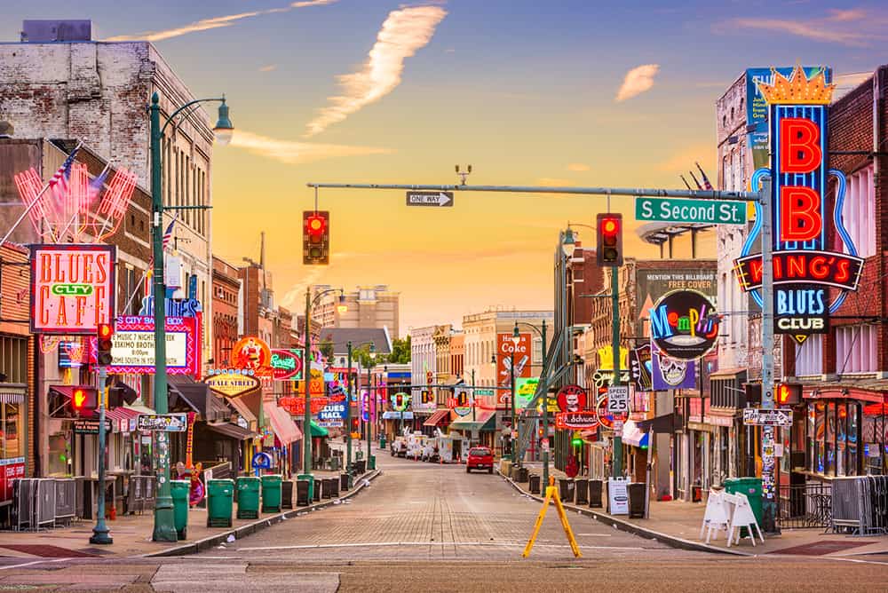 Beale Street at golden hour, neon signs lit down both sides of the block